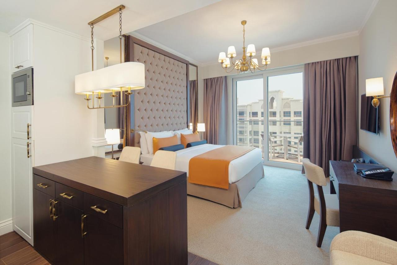 Dukes The Palm, A Royal Hideaway Hotel Dubai Exterior photo The photo shows a modern hotel room with a stylish design. The room features a large bed with orange and white bedding, complemented by a decorative headboard. There are two curtains framing a large window that allows natural light to fill the space.