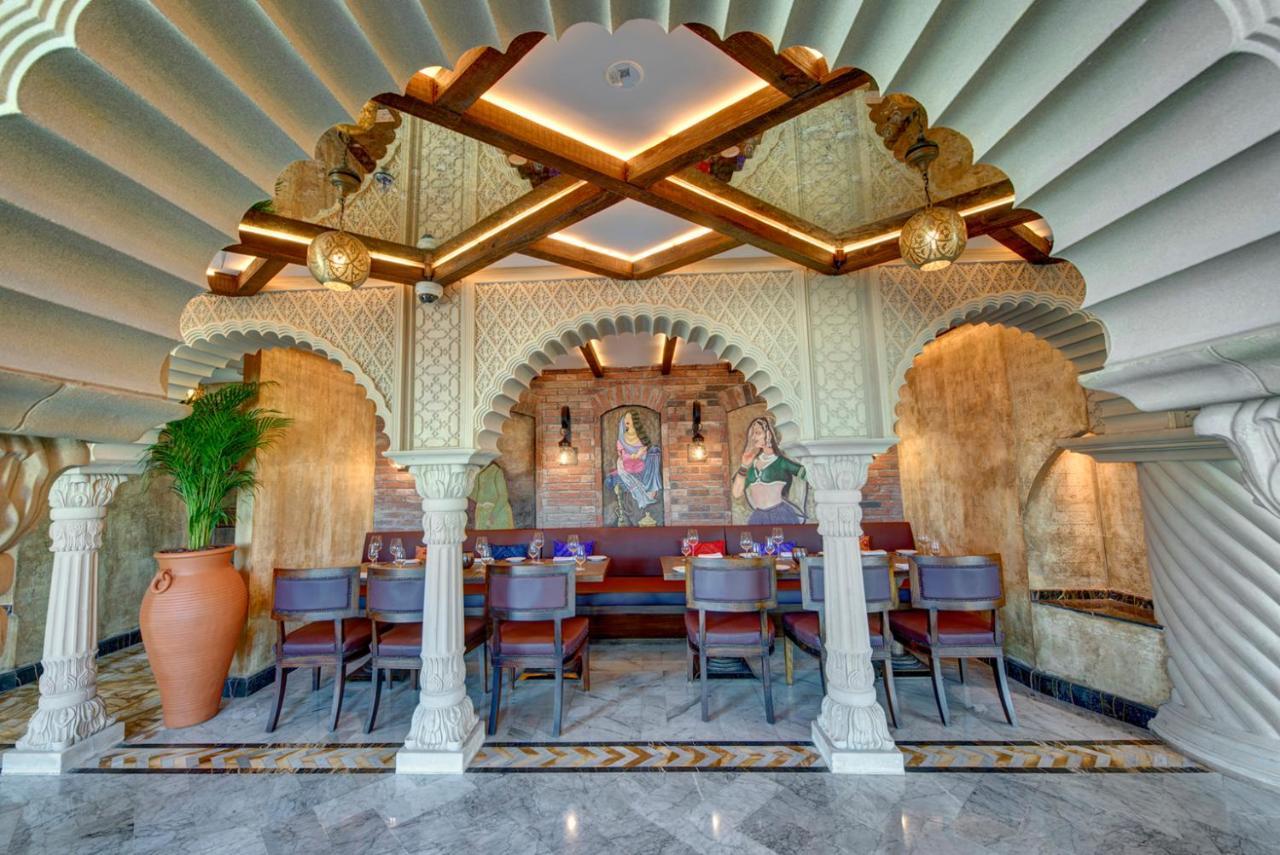 Dukes The Palm, A Royal Hideaway Hotel Dubai Exterior photo The photo showcases the interior design of a restaurant, characterized by a beautiful architectural style. There is an ornate archway supported by pillars, which adds a classical touch. The ceiling features a unique, layered design, creating an elega