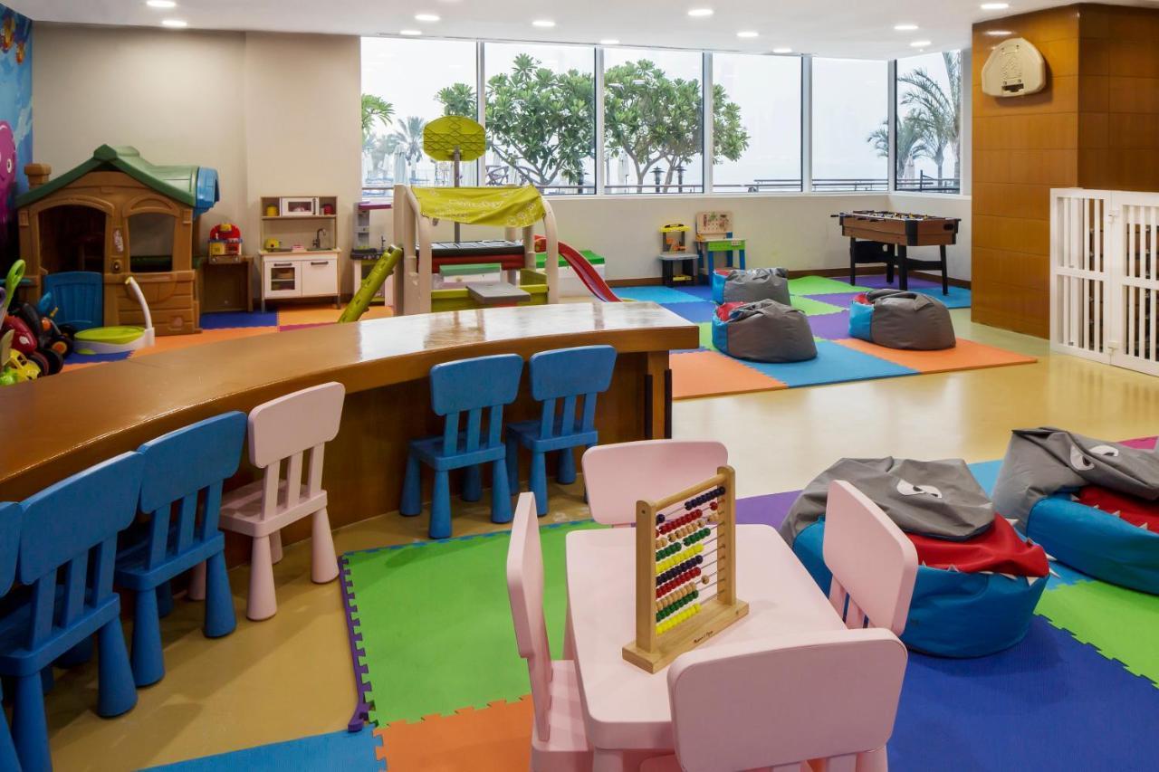 Dukes The Palm, A Royal Hideaway Hotel Dubai Exterior photo The photo shows a colorful indoor play area designed for children. The space features several elements, including:

- **Play Structures**: There is a small climbing structure with slides, along with a playhouse.
- **Furniture**: Brightly colored tabl