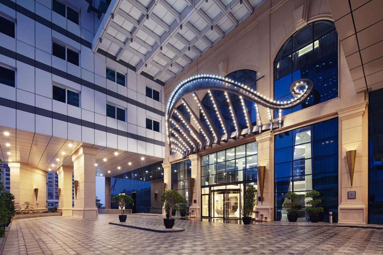 Dukes The Palm, A Royal Hideaway Hotel Dubai Exterior photo The photo shows the entrance of a modern building, likely a hotel or a prestigious office space. The facade features a prominent archway adorned with lights, creating an inviting and elegant atmosphere. The entrance has large glass doors, and there a