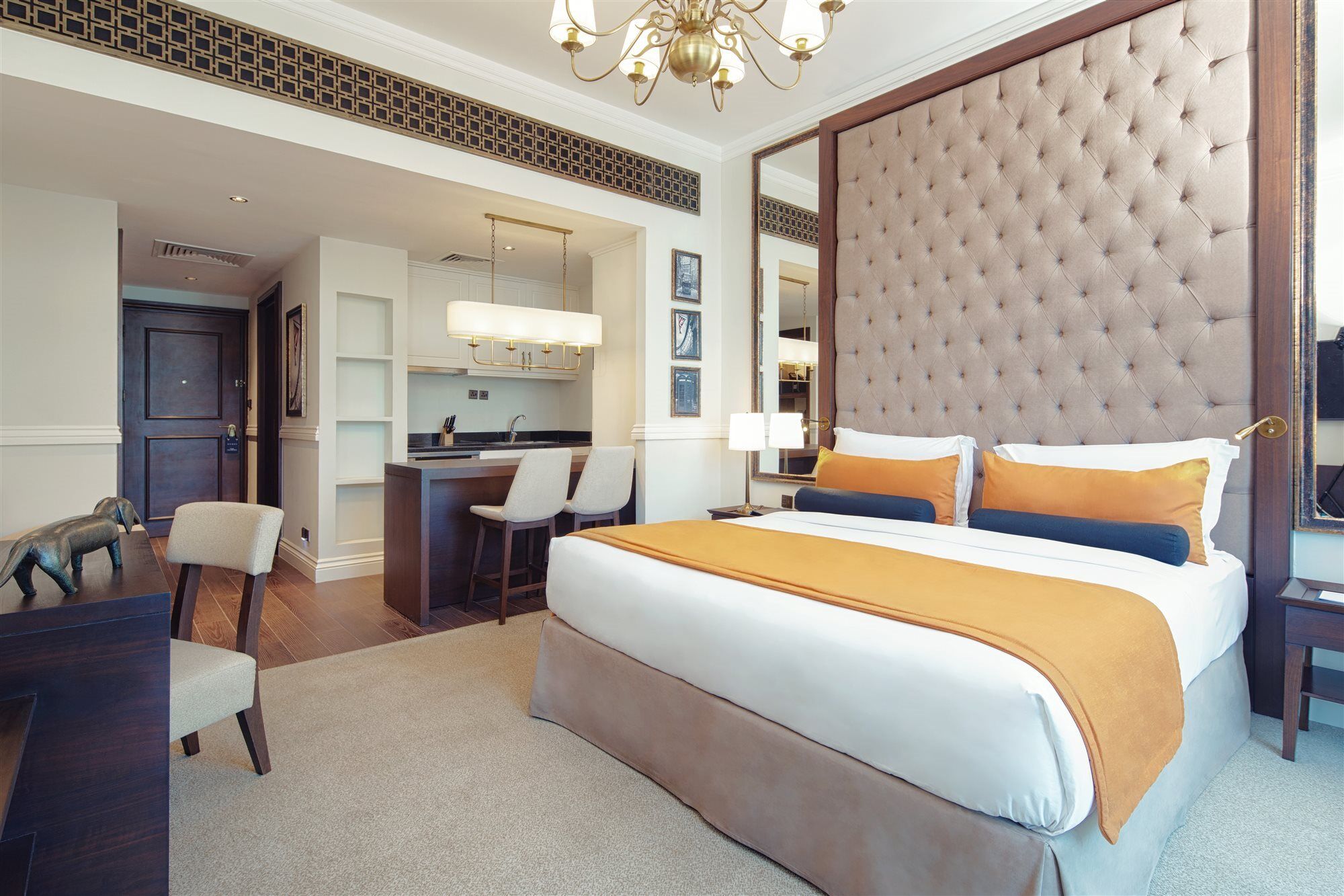 Dukes The Palm, A Royal Hideaway Hotel Dubai Exterior photo The image shows a modern hotel room featuring a stylish design. In the center, there's a large bed with a tufted headboard upholstered in light brown, complemented by two decorative pillows in blue and orange. The room has a neutral color scheme with